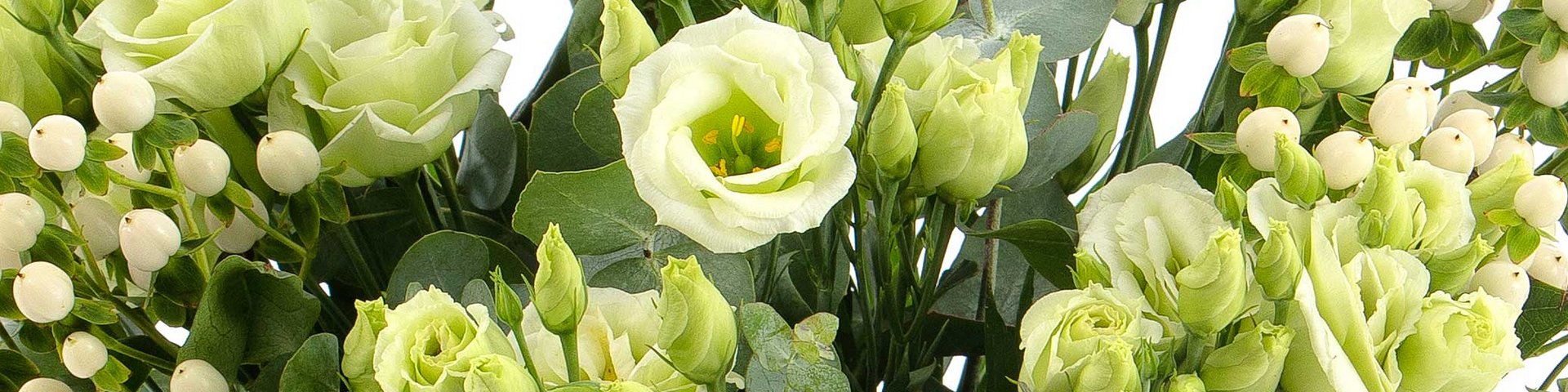 En buket bestående af forskellige lysegrønne blomster, herunder roser og små perleagtige blomster. Buketten er fyldt med grønne blade, der tilføjer dybde og tekstur til arrangementet.